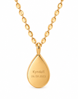 A gold teardrop pendant necklace engraved with the name 'Kyndall' and the date '06.09.