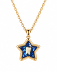 A gold star-shaped pendant necklace featuring a textured blue glittery inlay and a central white tooth charm, suspended from a gold chain on a white background.