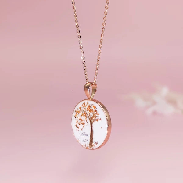 Rose gold breastmilk necklace with a tree design pendant on a pink background