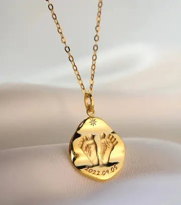 Gold footprint necklace with a heart-shaped pendant on a white background